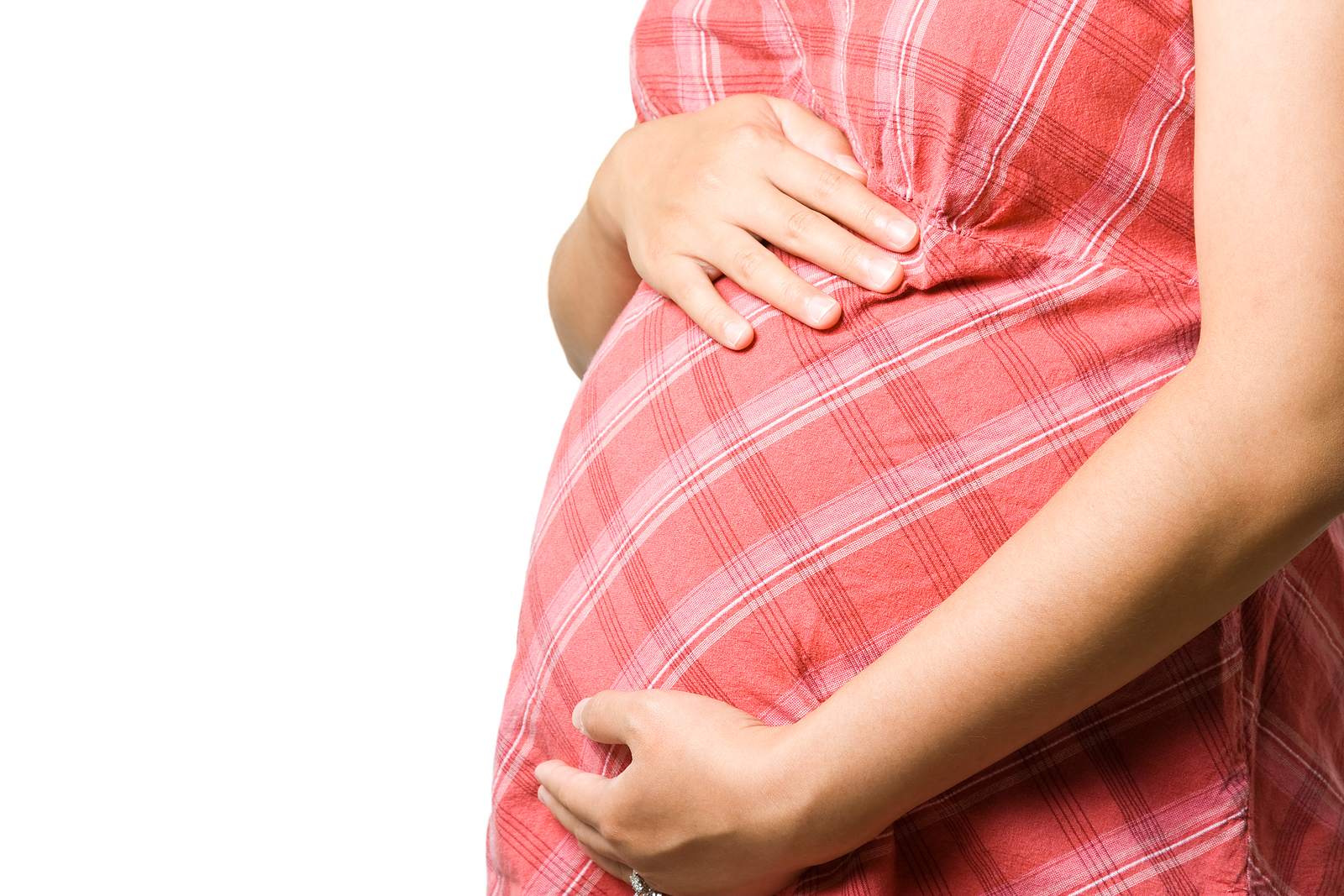 Close-up of pregnant woman in pink dress, gently putting her hands on her curved stomach
