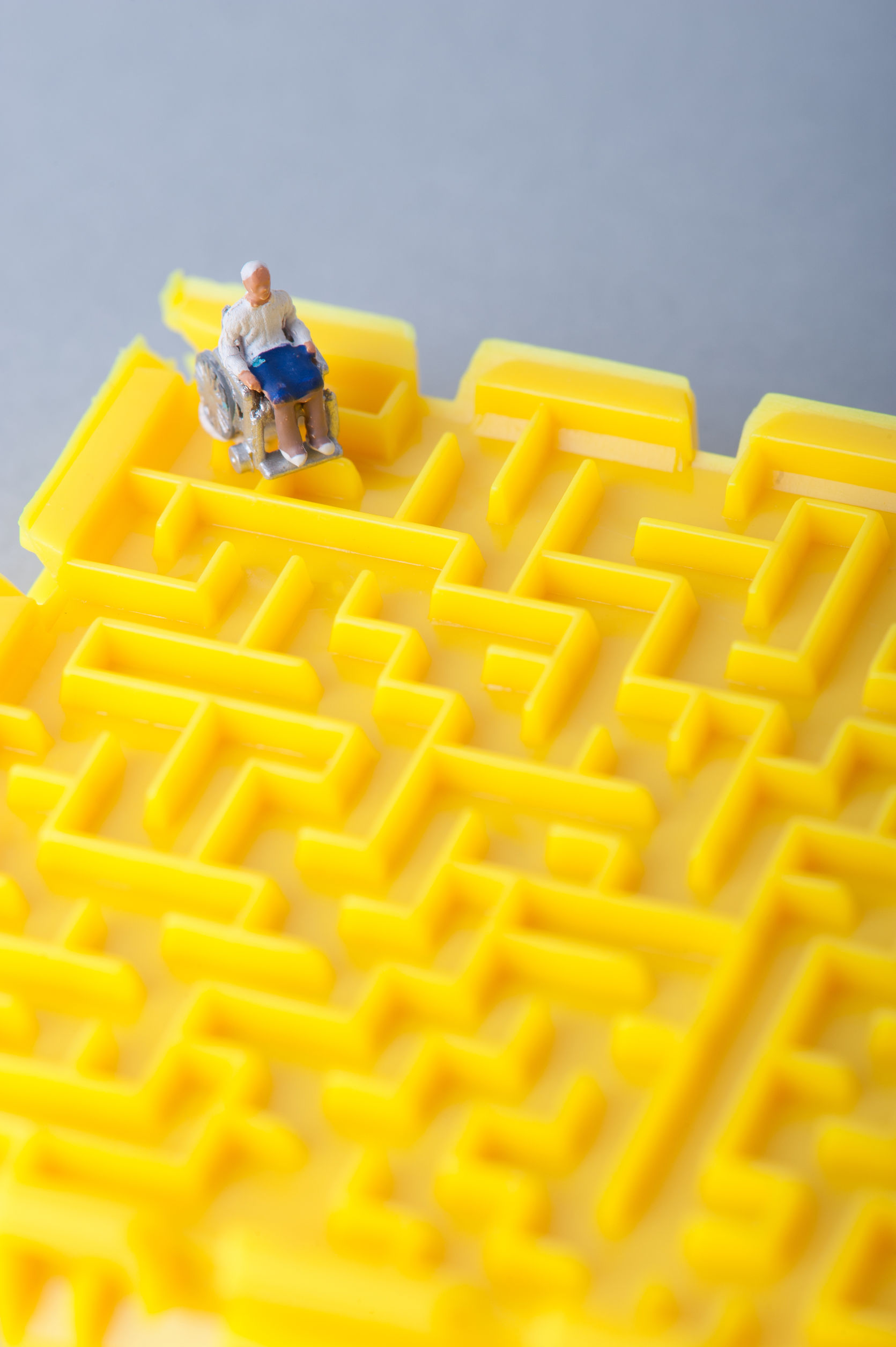 Miniature human in wheelchair and trapped in a yellow maze Miniature human in wheelchair and trapped in a yellow maze