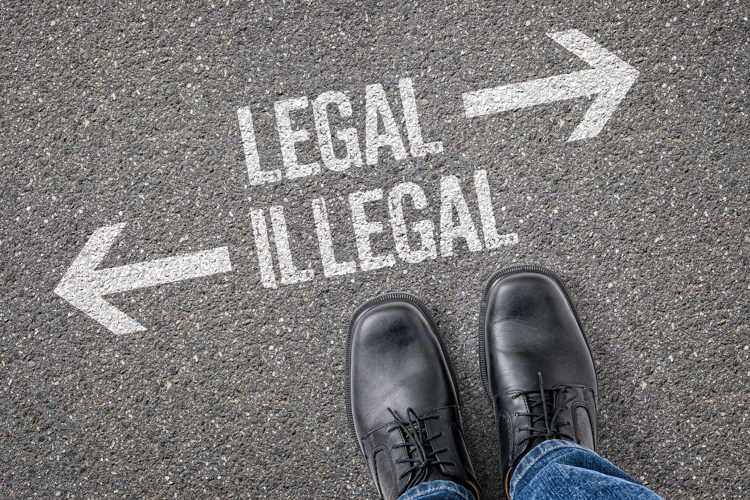 Photo of a tarmac road marked with opposite arrows, one saying "legal" and the other "illegal"