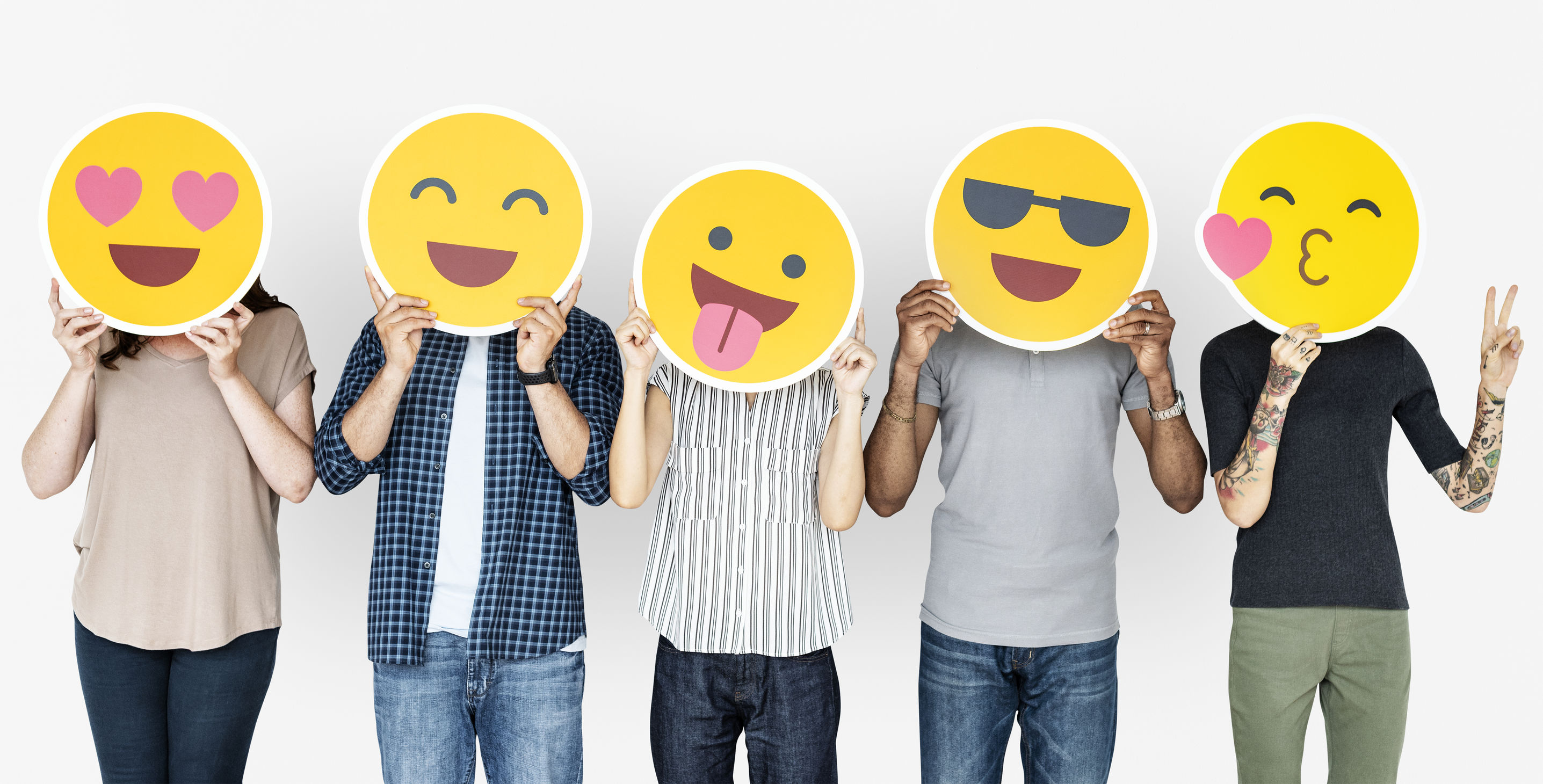 Five people standing side by side and holding up funny emoji icons in front of their faces