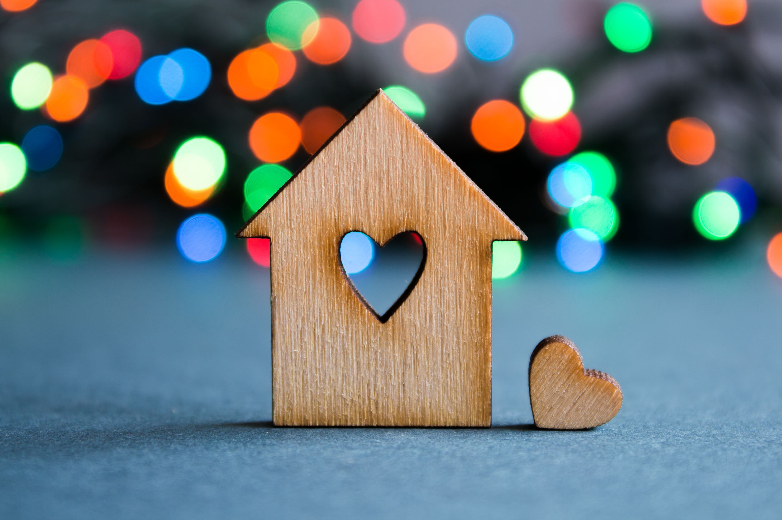 Small wooden model of a house, with a cut-out heart shape in the middle