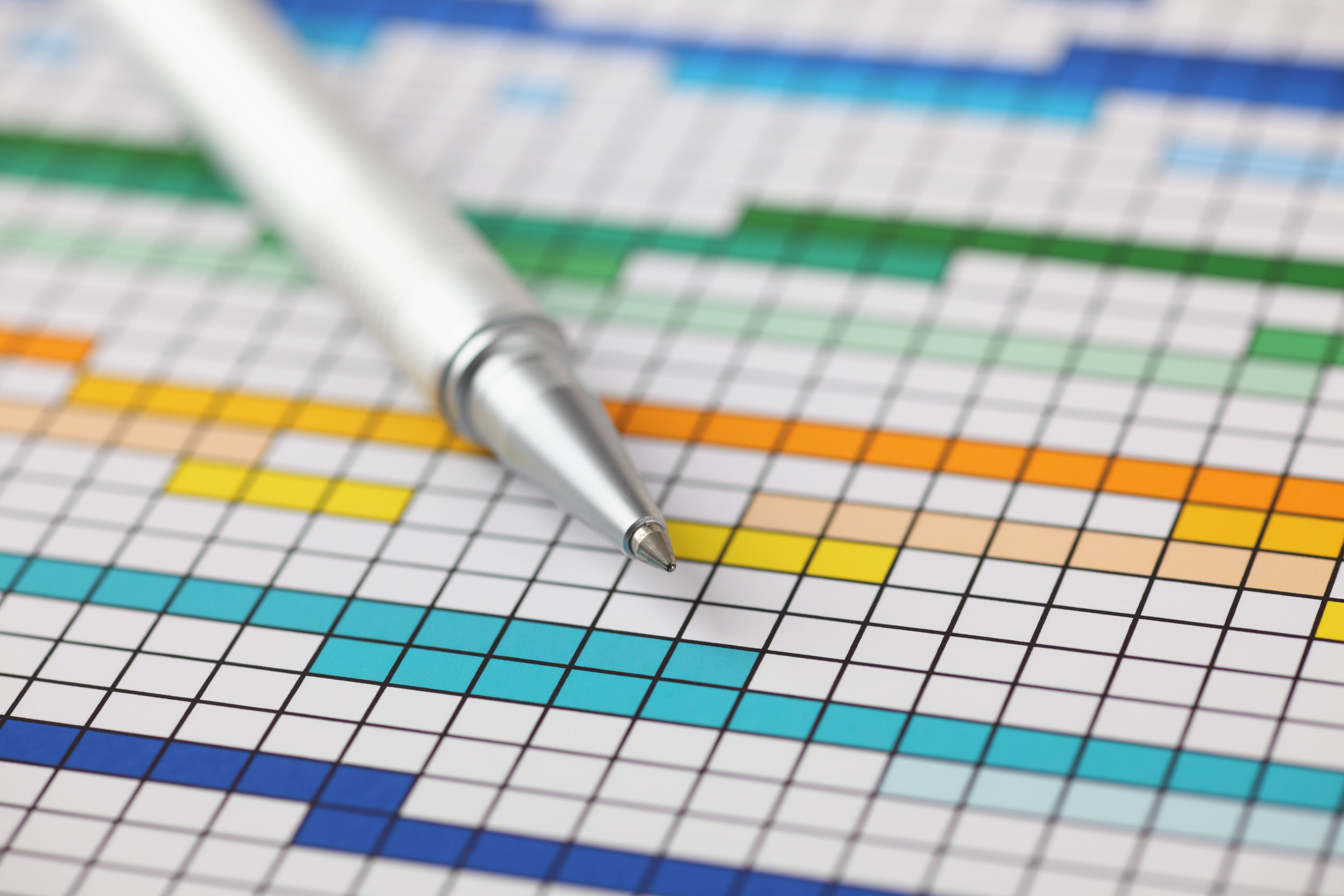 Photo of a pen placed above a piece of paper with coloured squares 