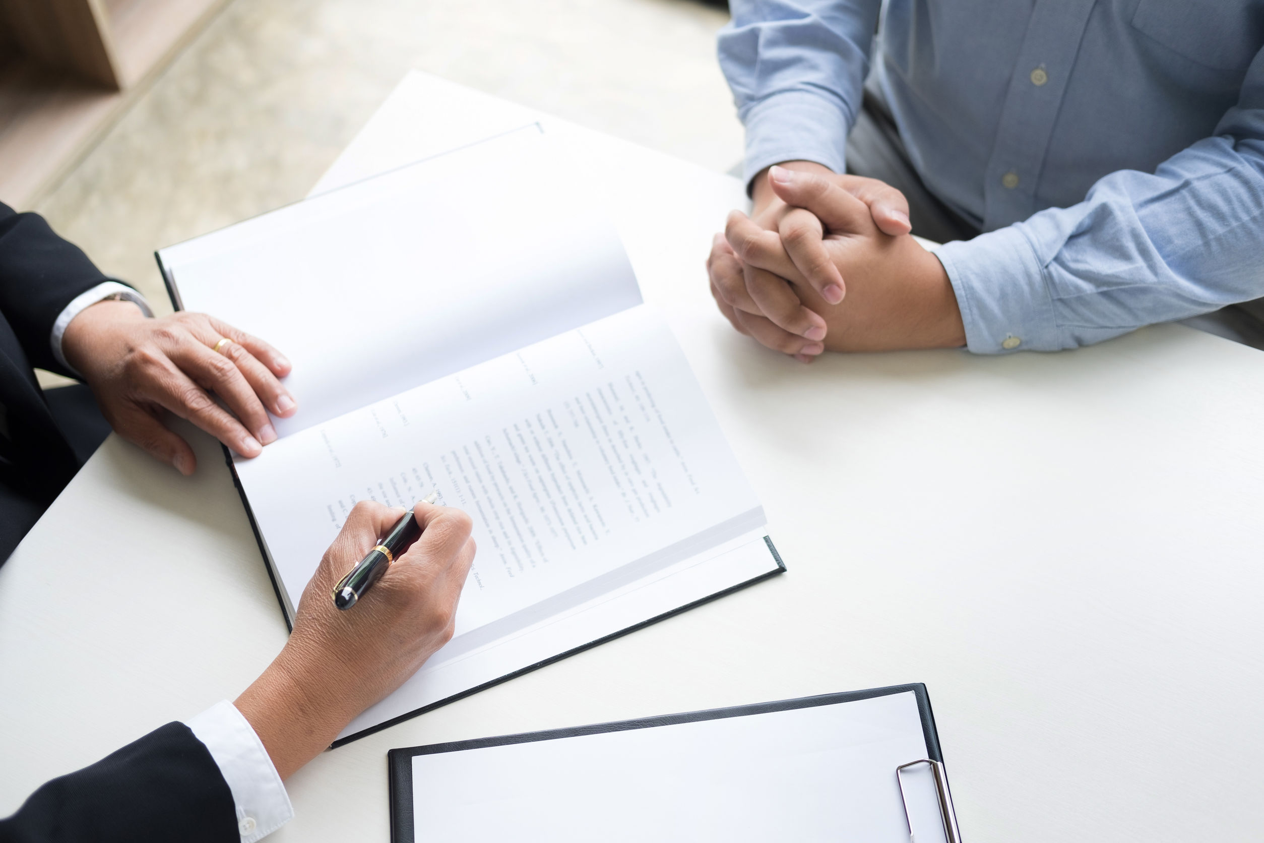 Photo of a person listening to another person talking and jotting down notes