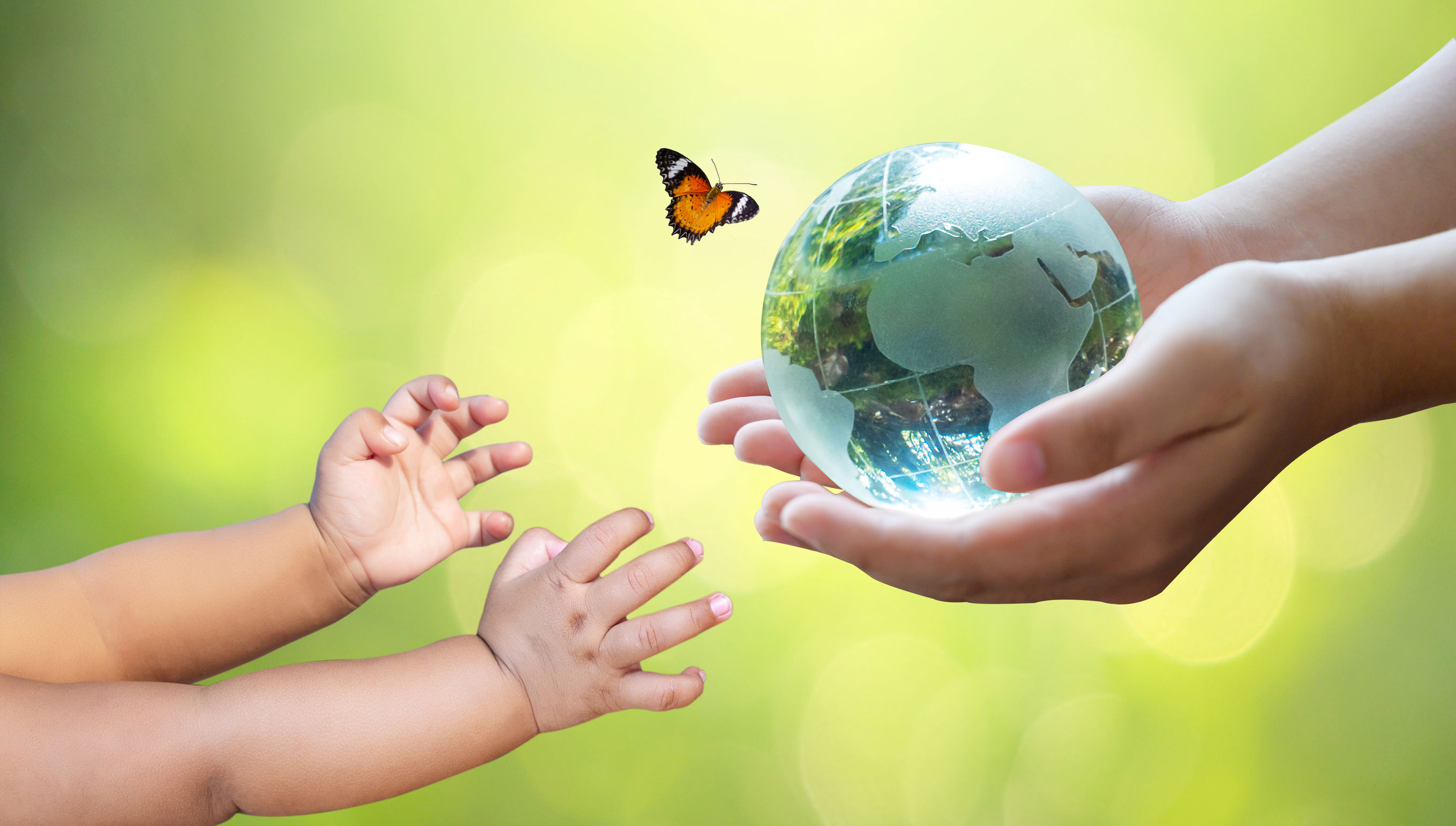 Photo of a parent’s hands passing a mini globe to a baby