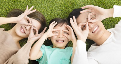 Parents and their daughter lie on grass happily