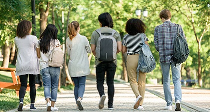 Six young people are walking on a path with trees around