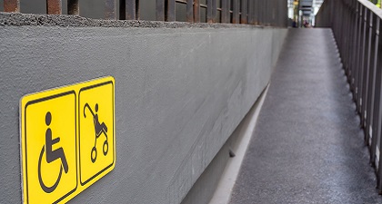 A ramp on a building with wheelchair and stroller signs on wall